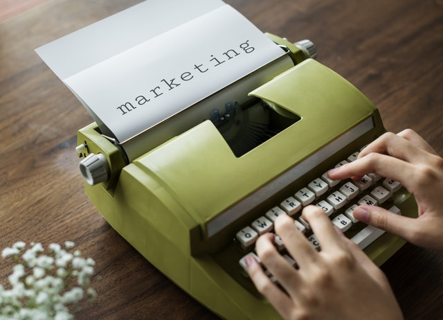 Manos escribiendo la palabra Marketing en una máquina de escribir